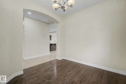 Open concept interior featuring dark wood-finish flooring, light-colored walls, and a decorative ceiling light fixture - 6016 10 Avenue Sw, Edmonton, AB - Indoor Photo Showing Other Room