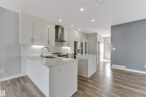 Open-concept kitchen featuring white shaker cabinetry, stainless steel appliances, and a double-basin sink - 6075 180 Avenue Nw, Edmonton, AB - Indoor Photo Showing Kitchen With Double Sink With Upgraded Kitchen