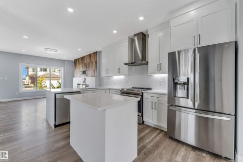 Modern kitchen featuring white shaker cabinetry, stainless steel appliances, and wood-finish flooring - 6075 180 Avenue Nw, Edmonton, AB - Indoor Photo Showing Kitchen With Stainless Steel Kitchen With Upgraded Kitchen