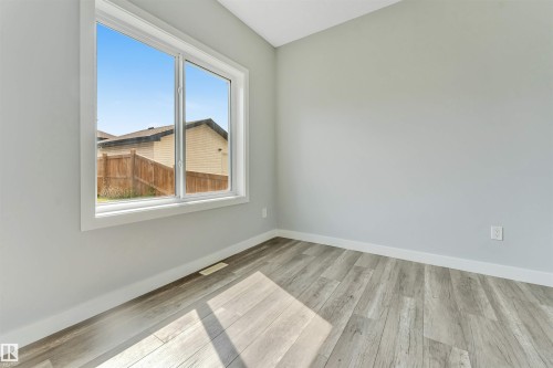 Room featuring a large white-framed window, light grey walls, and wood-finish flooring - 6075 180 Avenue Nw, Edmonton, AB - Indoor Photo Showing Other Room