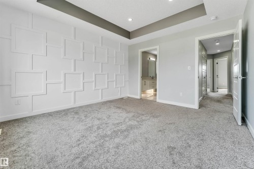 Feature wall with decorative molding, recessed ceiling, recessed lighting, light gray carpeting, and white interior doors - 6075 180 Avenue Nw, Edmonton, AB - Indoor Photo Showing Other Room