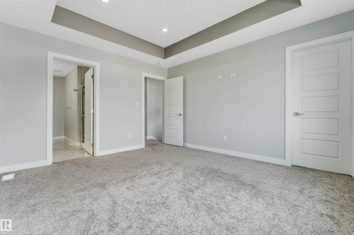 Spacious room featuring tray ceiling details, recessed lighting, neutral wall tones, and plush carpet flooring - 6075 180 Avenue Nw, Edmonton, AB - Indoor Photo Showing Other Room