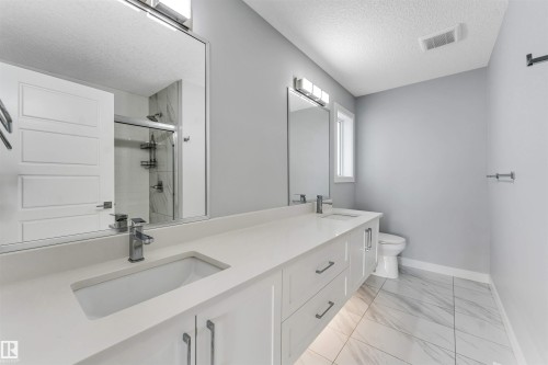 Double vanity with white cabinetry, integrated sinks, and polished chrome fixtures - 6075 180 Avenue Nw, Edmonton, AB - Indoor Photo Showing Bathroom