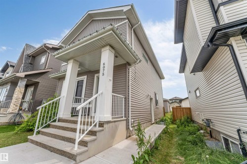 Exterior facade featuring horizontal siding, a covered entry, and concrete steps with white railings - 6075 180 Avenue Nw, Edmonton, AB - Outdoor