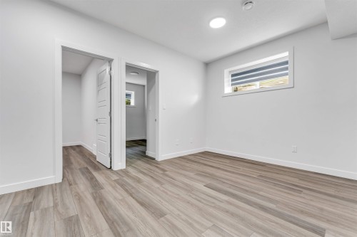 Spacious room featuring wood-finish flooring, white walls, and a recessed ceiling light - 6075 180 Avenue Nw, Edmonton, AB - Indoor Photo Showing Other Room