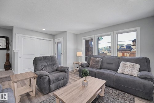 Living area featuring wood-finish flooring, light gray wall paint, recessed lighting, and multiple windows with white trim - 2314 Wonnacott Crescent Sw, Edmonton, AB - Indoor Photo Showing Living Room