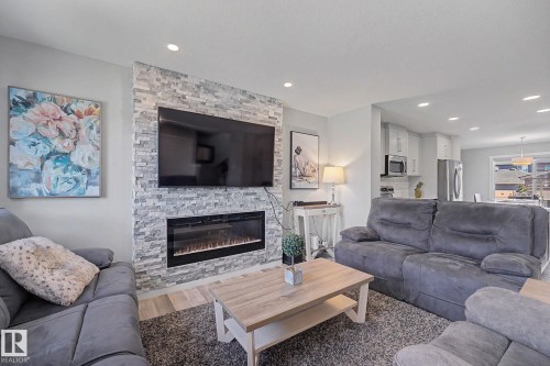 Living area featuring a floor-to-ceiling stacked stone fireplace surround with an inset electric fireplace - 2314 Wonnacott Crescent Sw, Edmonton, AB - Indoor Photo Showing Living Room With Fireplace