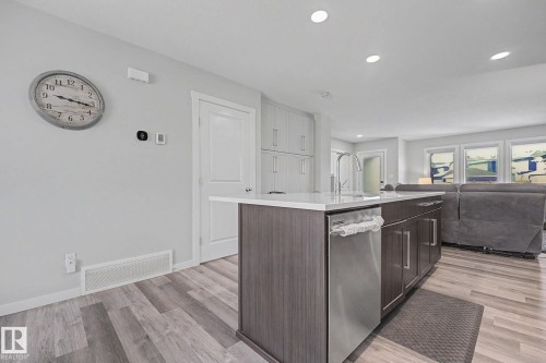 Kitchen island featuring a white countertop, under-mount sink, and stainless steel dishwasher - 2314 Wonnacott Crescent Sw, Edmonton, AB - Indoor Photo Showing Kitchen