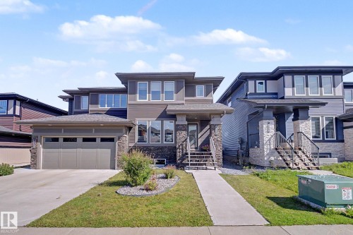 Modern two-story residence featuring a two-car garage, stone and siding exterior, multiple large windows, and a concrete driveway - 2314 Wonnacott Crescent Sw, Edmonton, AB - Outdoor With Facade