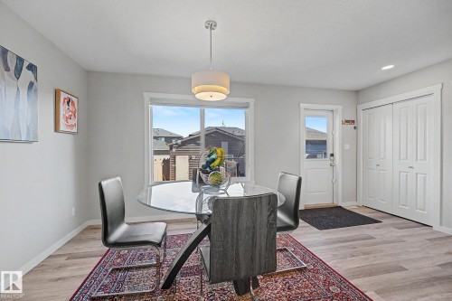 Dining area featuring a contemporary chandelier, large window, and wood-finish flooring - 2314 Wonnacott Crescent Sw, Edmonton, AB - Indoor Photo Showing Dining Room