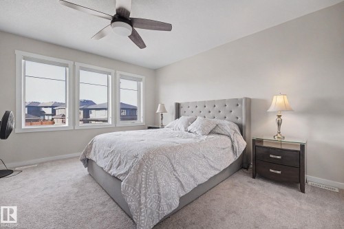 Bedroom featuring light gray carpeting and three large windows with white trim - 2314 Wonnacott Crescent Sw, Edmonton, AB - Indoor Photo Showing Bedroom