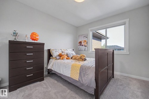 Carpeted room featuring a large window, light-colored walls, and a ceiling-mounted light fixture - 2314 Wonnacott Crescent Sw, Edmonton, AB - Indoor Photo Showing Bedroom