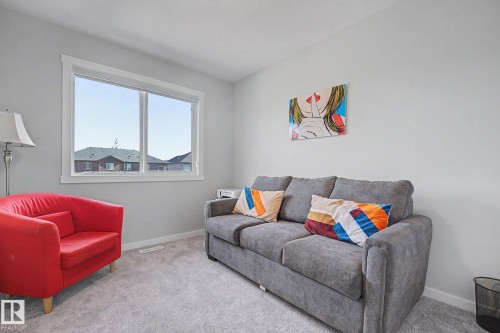 Room featuring a large white-trimmed window, light gray walls, and light gray carpeting - 2314 Wonnacott Crescent Sw, Edmonton, AB - Indoor Photo Showing Other Room