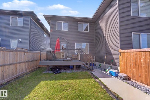 Rear exterior featuring an elevated deck with metal railings, a ground-level grass area, and privacy fencing - 2314 Wonnacott Crescent Sw, Edmonton, AB - Outdoor With Deck Patio Veranda With Exterior