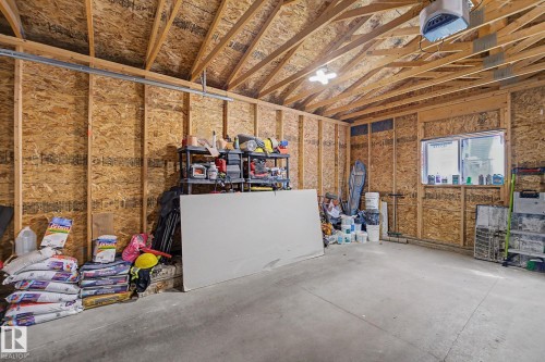 Spacious garage featuring exposed wood framing, an overhead garage door opener, concrete flooring, and a single window for natural light - 2314 Wonnacott Crescent Sw, Edmonton, AB - Indoor