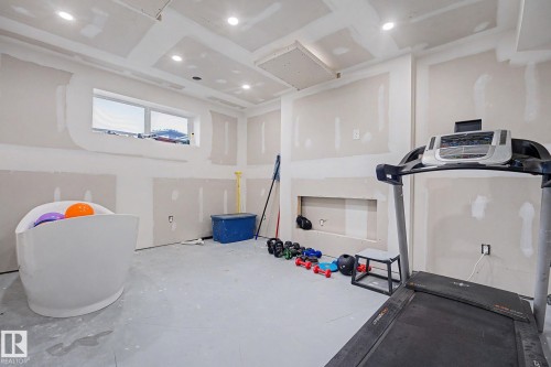 Unfinished interior space featuring drywall installation, recessed lighting, a built-in niche, and a window providing natural illumination - 2314 Wonnacott Crescent Sw, Edmonton, AB - Indoor