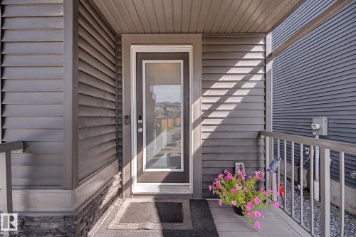 Covered front porch featuring gray horizontal siding and a full-light storm door - 2314 Wonnacott Crescent Sw, Edmonton, AB - Outdoor With Exterior