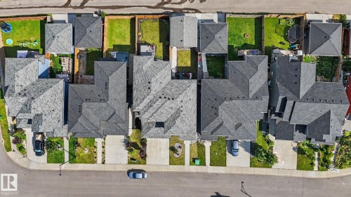Aerial view of residential properties with asphalt shingle roofs and concrete driveways, featuring private fenced backyards with green lawns - 2314 Wonnacott Crescent Sw, Edmonton, AB - Outdoor