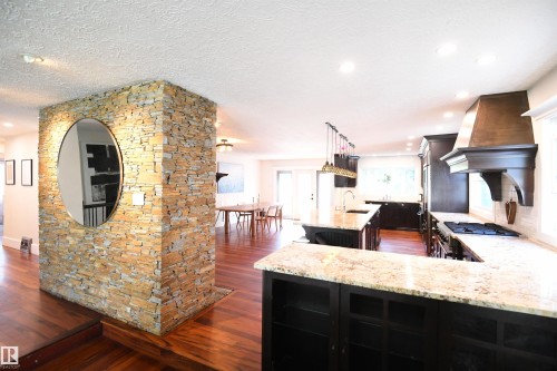 The kitchen is simply stunning.  Dark, maple cabinetry, granite counters, TWO ovens, THREE undermount sinks, a Sub Zero fridge, gas stove, custom range hood, and a phenomenal 13 foot long island, with seating for 6.  Amazing Kitchen - 572 Lessard Drive Nw, Edmonton, AB - Indoor Photo Showing Kitchen