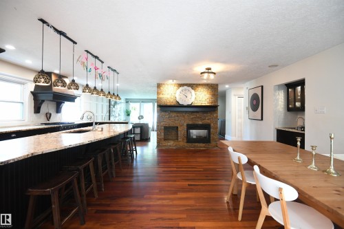 The kitchen is simply stunning.  Dark, maple cabinetry, granite counters, TWO ovens, THREE undermount sinks, a Sub Zero fridge, gas stove, custom range hood, and a phenomenal 13 foot long island, with seating for 6.  Amazing Kitchen - 572 Lessard Drive Nw, Edmonton, AB - Indoor Photo Showing Dining Room With Fireplace