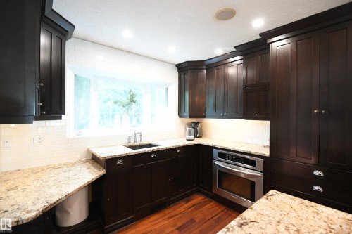 The work sink is set away from the entertaining area of the kitchen island.  Combined with the large undermount sink in the island, and the bar sink on the opposite wall, there is plenty of space for all the aspiring chefs in the family to help out - 572 Lessard Drive Nw, Edmonton, AB - Indoor Photo Showing Kitchen