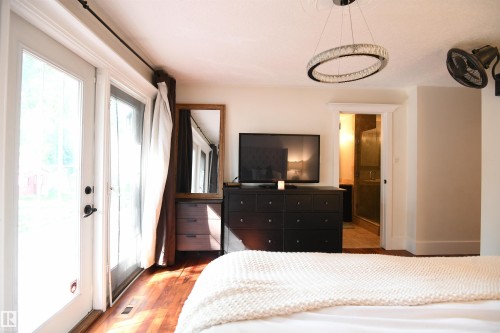 The master suite easily supports king sized furniture and has great private access to the rear yard and patio.  A large walk in closet, and fully features ensuite, with a glass walled shower round out this great space - 572 Lessard Drive Nw, Edmonton, AB - Indoor Photo Showing Bedroom
