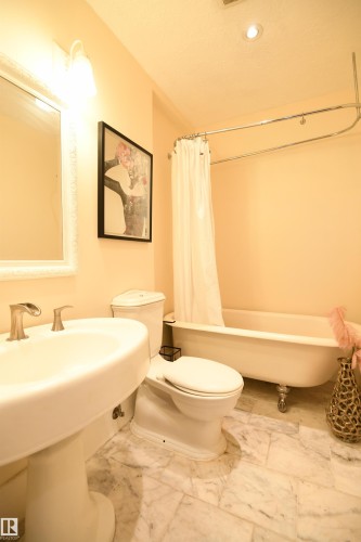The main bathroom is quipped with a clawfoot tub, pedestal sink, and marble accents - 572 Lessard Drive Nw, Edmonton, AB - Indoor Photo Showing Bathroom