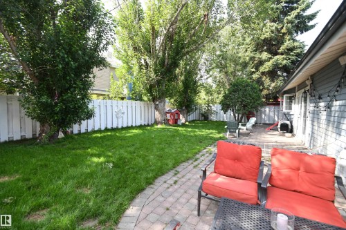 Fully fenced, treed, and with a full width patio with a natural gas firepit, the rear yard is a wonderful place to enjoy family and entertaining time - 572 Lessard Drive Nw, Edmonton, AB - Outdoor