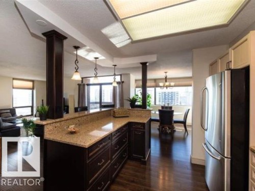 Expansive kitchen island with granite countertop and rich wood-finish cabinetry - #1203 10025 113 St Nw, Edmonton, AB - Indoor Photo Showing Kitchen