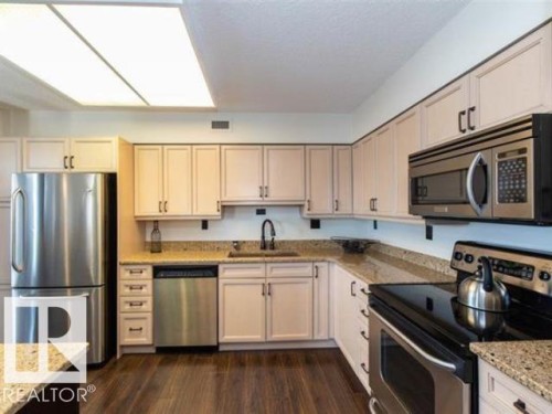 Kitchen featuring wood-finish flooring, granite countertops, and light cabinetry with black hardware - #1203 10025 113 St Nw, Edmonton, AB - Indoor Photo Showing Kitchen