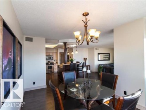 Formal dining area featuring a bronze chandelier, wood-finish flooring, and crown molding - #1203 10025 113 St Nw, Edmonton, AB - Indoor Photo Showing Dining Room