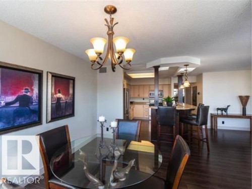 Dining area featuring a bronze chandelier, dark wood-finish flooring, and an open-concept design to the kitchen - #1203 10025 113 St Nw, Edmonton, AB - Indoor Photo Showing Dining Room