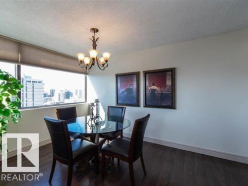 Dining area featuring wood-finish flooring, a contemporary chandelier, and a wall of windows - #1203 10025 113 St Nw, Edmonton, AB - Indoor Photo Showing Dining Room