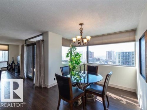 Dining area featuring wide plank wood-finish flooring, a multi-pane window, and a five-light chandelier - #1203 10025 113 St Nw, Edmonton, AB - Indoor Photo Showing Dining Room