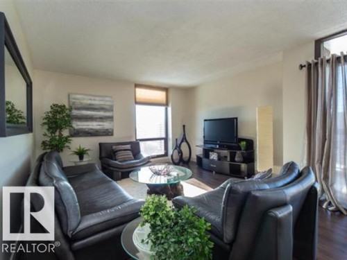 Living area with wood-finish flooring, ample natural light from a large window, neutral wall tones, and ceiling texture - #1203 10025 113 St Nw, Edmonton, AB - Indoor Photo Showing Living Room