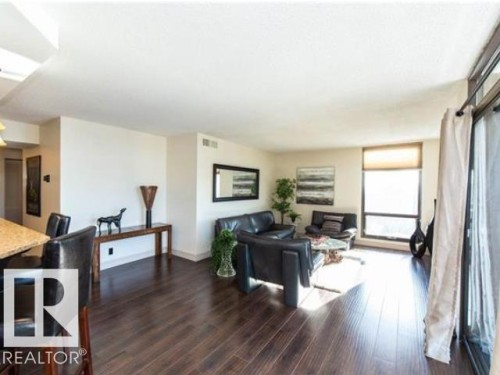 Open-concept living space featuring wood-finish flooring, a full-height window, and light-toned walls - #1203 10025 113 St Nw, Edmonton, AB - Indoor Photo Showing Living Room