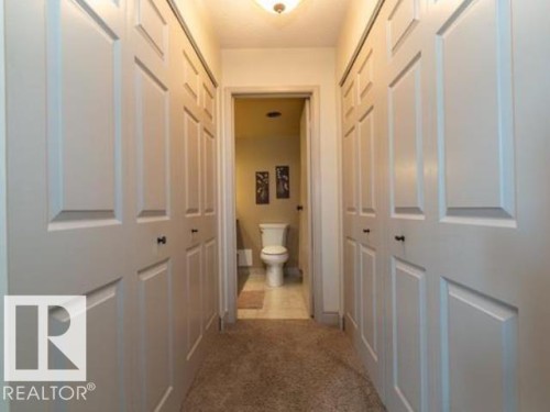 Hallway featuring carpet flooring and multiple paneled bi-fold doors - #1203 10025 113 St Nw, Edmonton, AB - Indoor Photo Showing Other Room