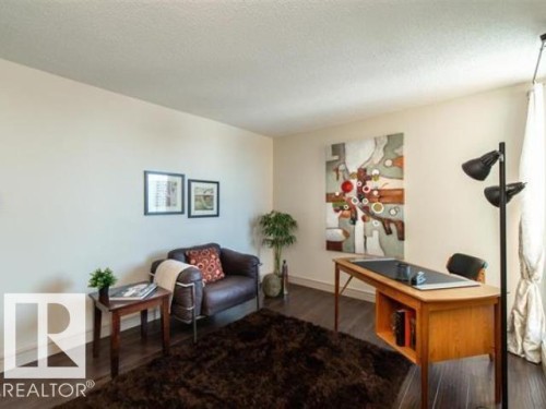 Interior space featuring wood-finish flooring, light-toned walls, and a large window with drapes - #1203 10025 113 St Nw, Edmonton, AB - Indoor