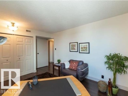 Interior room featuring wood-finish flooring, white walls, and a white ceiling with a flush-mount light fixture - #1203 10025 113 St Nw, Edmonton, AB - Indoor