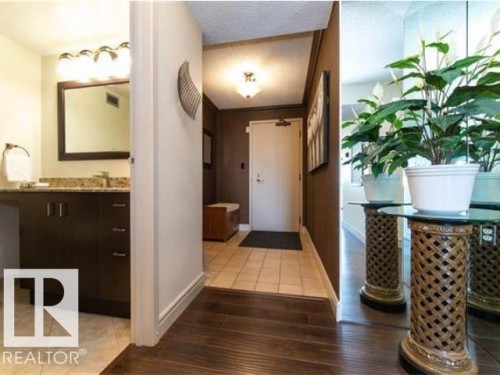 Bathroom entry featuring a dark wood-finish vanity with a stone countertop, an undermount sink, and a framed mirror - #1203 10025 113 St Nw, Edmonton, AB - Indoor Photo Showing Other Room