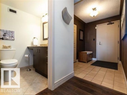 Entryway featuring a solid core door, crown molding, and a flush mount ceiling fixture - #1203 10025 113 St Nw, Edmonton, AB - Indoor Photo Showing Bathroom