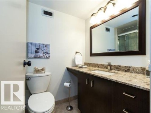 Vanity featuring a stone countertop, an undermount sink, and dark wood cabinetry with brushed nickel hardware - #1203 10025 113 St Nw, Edmonton, AB - Indoor Photo Showing Bathroom