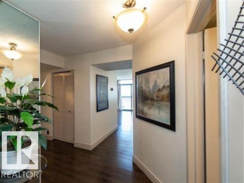 Hallway featuring dark wood-finish flooring, white baseboards, and neutral wall tones - #1203 10025 113 St Nw, Edmonton, AB - Indoor Photo Showing Other Room