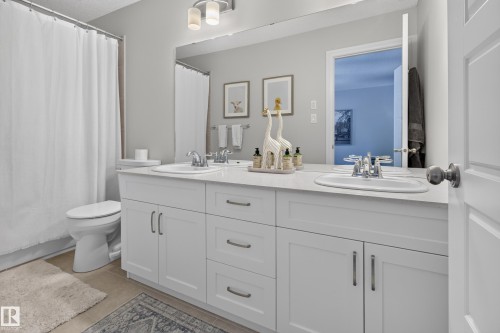 Bathroom featuring a double vanity with white cabinetry, integrated sinks, and polished chrome fixtures - 6 Daniel Street, Fort Saskatchewan, AB - Indoor Photo Showing Bathroom