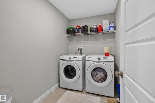 Dedicated laundry area featuring a front-load washer and dryer, tile flooring, and a built-in wire shelving unit - 6 Daniel Street, Fort Saskatchewan, AB - Indoor Photo Showing Laundry Room