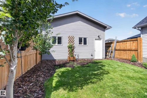 Rear exterior featuring grey siding, a white service door, and two windows - 6 Daniel Street, Fort Saskatchewan, AB - Outdoor With Exterior