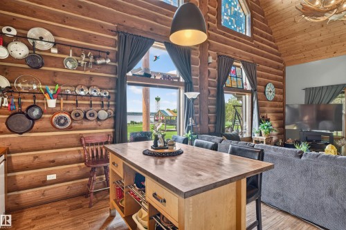 Open-concept living space with log walls, wood-finish flooring, and a vaulted wood-paneled ceiling - 107 Idlehours Drive, Rural Barrhead County, AB - Indoor