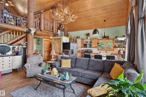 Open-concept living space featuring vaulted wood-paneled ceilings, a log beam stairway, and wood-finish flooring - 107 Idlehours Drive, Rural Barrhead County, AB - Indoor Photo Showing Living Room