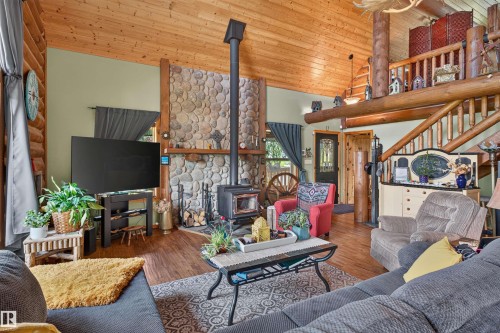 Vaulted wood-paneled ceiling with exposed log beams throughout this living area - 107 Idlehours Drive, Rural Barrhead County, AB - Indoor Photo Showing Living Room With Fireplace