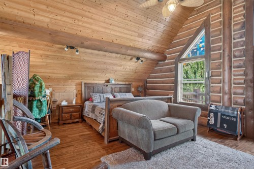 Wood-finish flooring throughout, featuring a vaulted ceiling with exposed wood beams and track lighting - 107 Idlehours Drive, Rural Barrhead County, AB - Indoor Photo Showing Bedroom